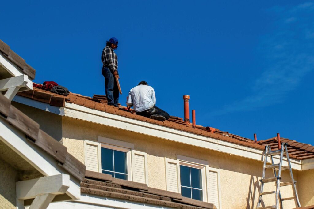 Roof workers repairing damaged shingles on a house to prevent further damage